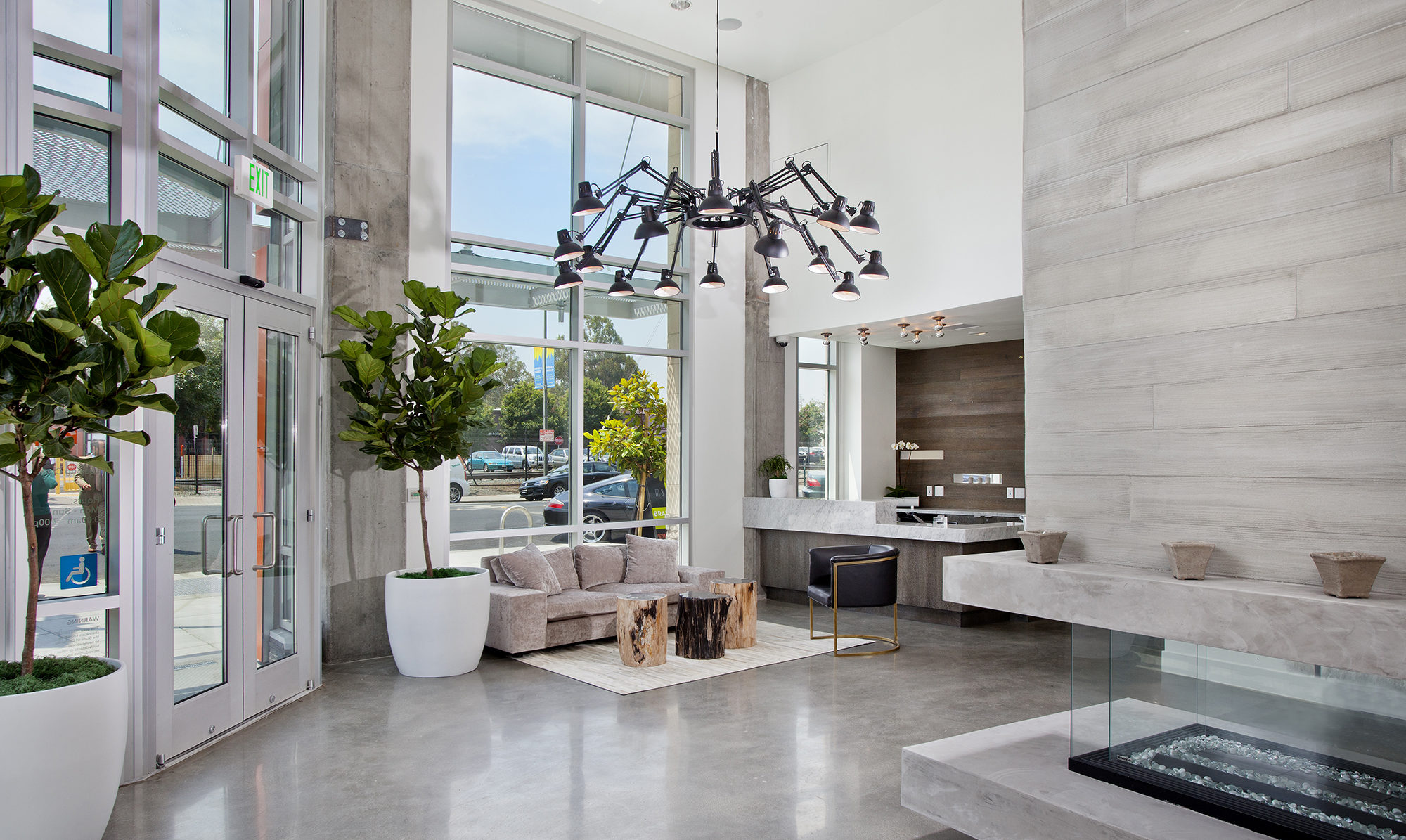 Interior of lobby space viewing out to the street with ceiling to roof windows and entrance doors.