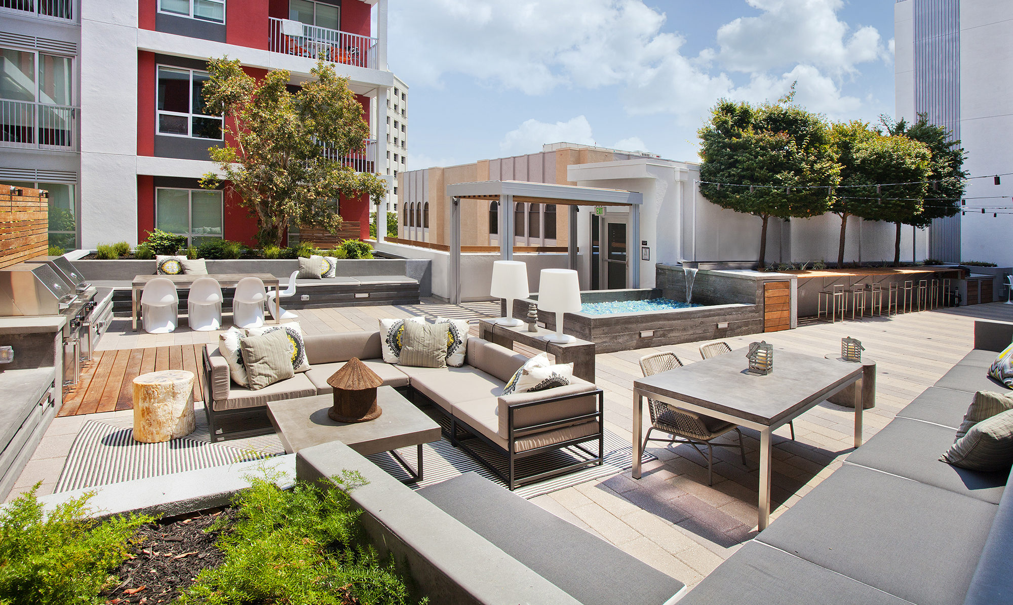 Courtyard area with barbecues, seating areas, and fountain surrounded by apartment units.