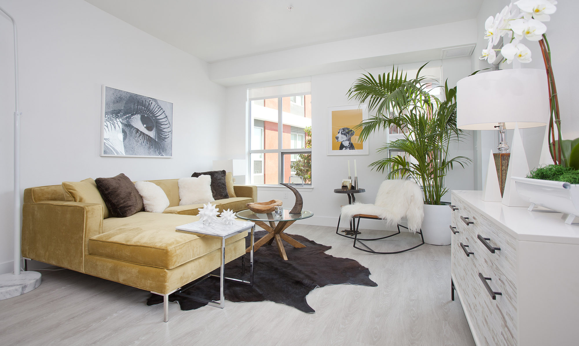 Interior of furnished living space in a unit with white walls and light floors.