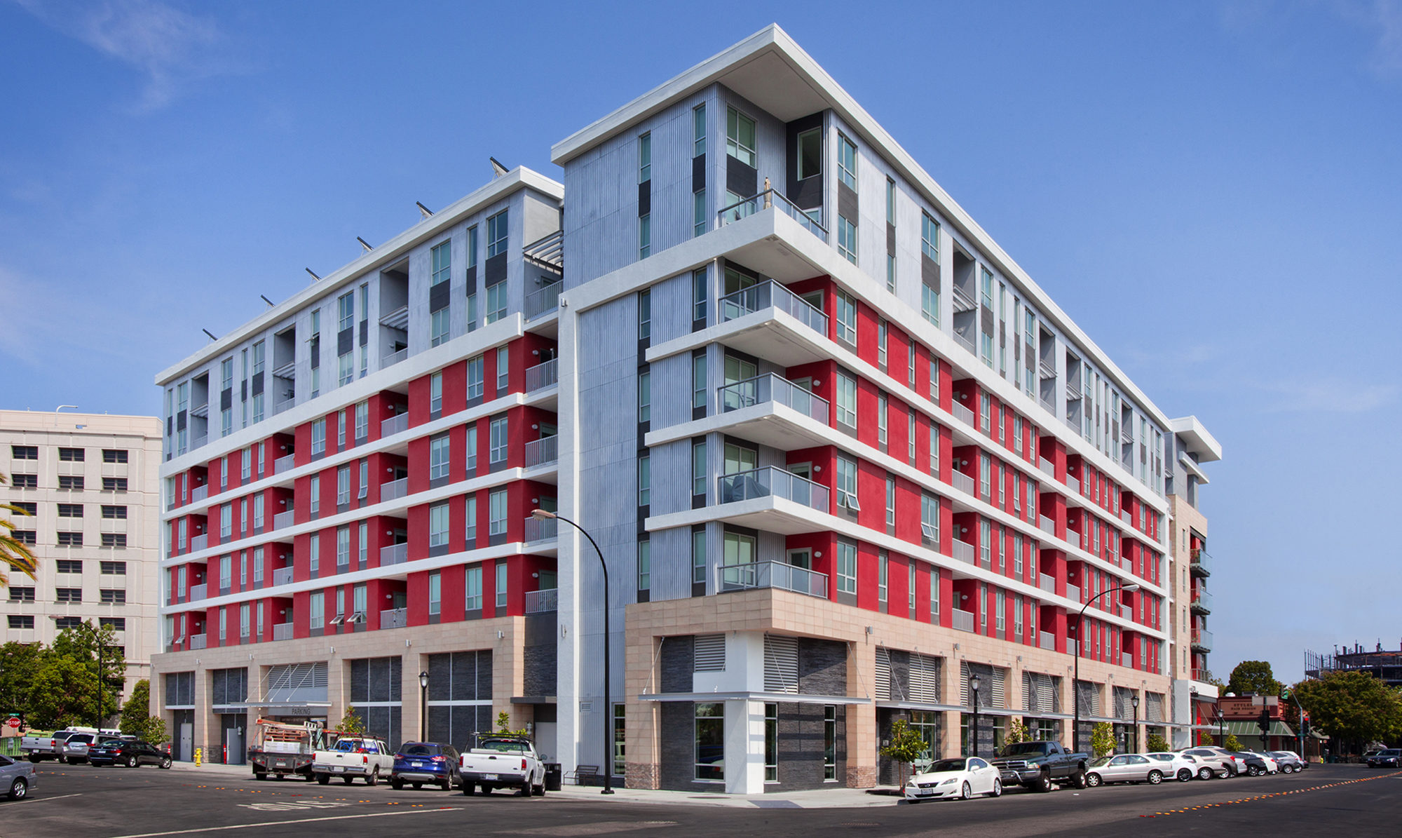 Back of podium building from street view with a lot of windows and balconies, along with red accent panels.