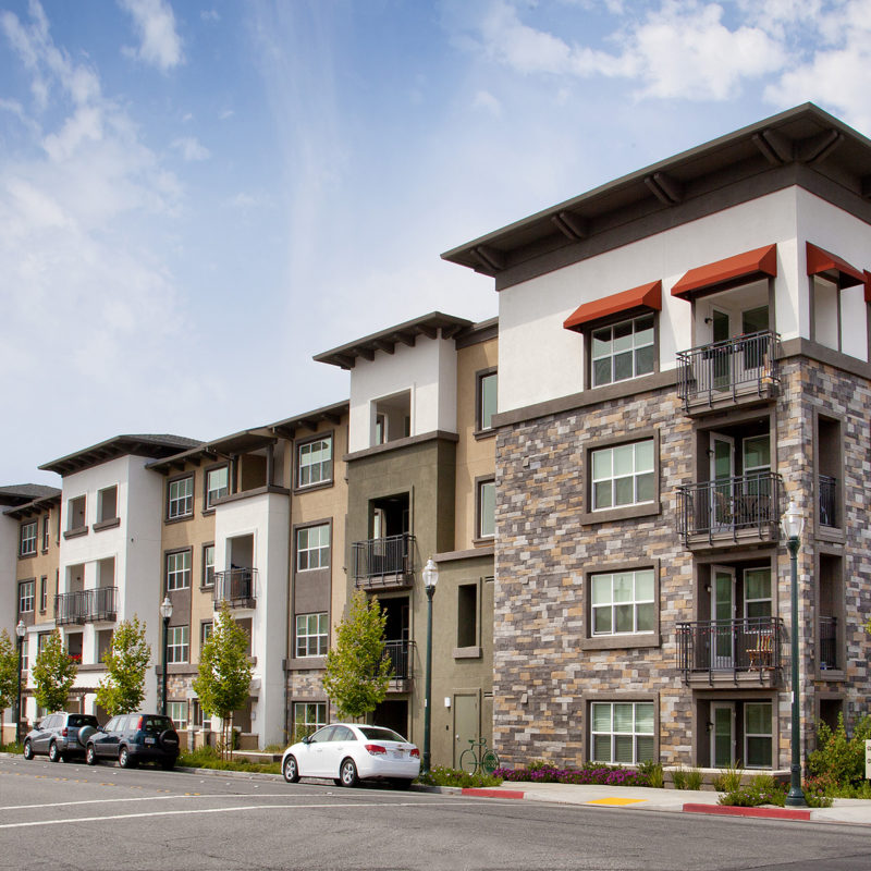 Front view of walk up with varying green, tan and stone along the facade